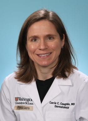 A white woman with short brown hair parted on the right side wearing a black shirt under a doctor's white coat embroidered with her name on the right and Washington University School of Medicine on the left