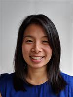 An Asian woman smiling with short black hair to her shoulders wearing a dark blue shirt