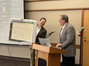 Dr. Mark Valentine explains a framed chart from 1876 listing dermatology diagnoses with their characteristics and treatments.