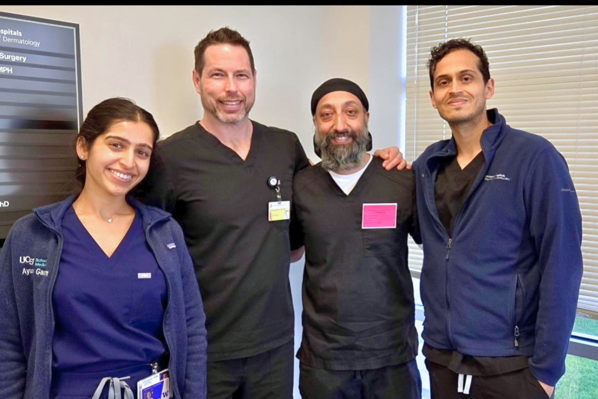 A woman and three men in scrubs smiling at the camera